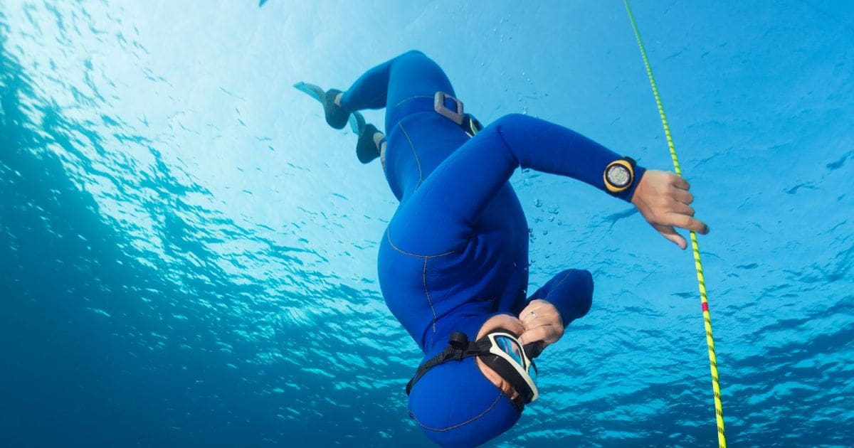 man freediving under water
